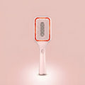 Elara Red Light Brush shown upright, white paddle brush with a glowing red LED ring around the bristles.